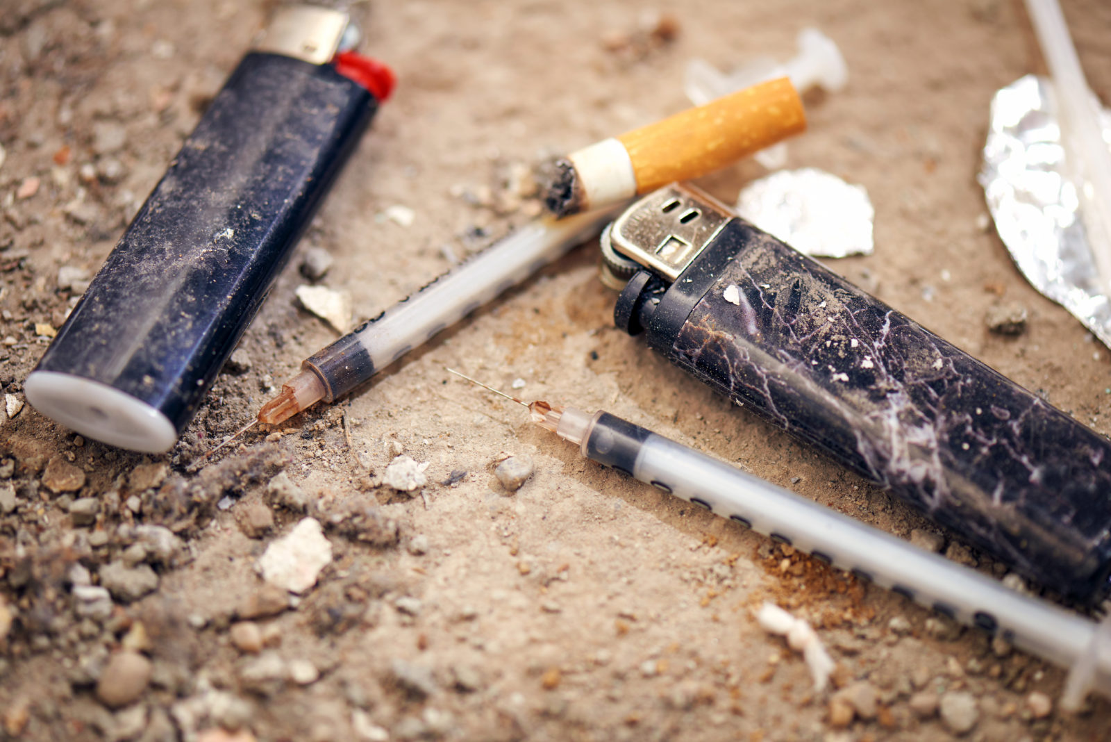 Used syringe on the ground - drugs Addiction equipment. Heroin, syringe, cigarette and lighter - drug addiction concept