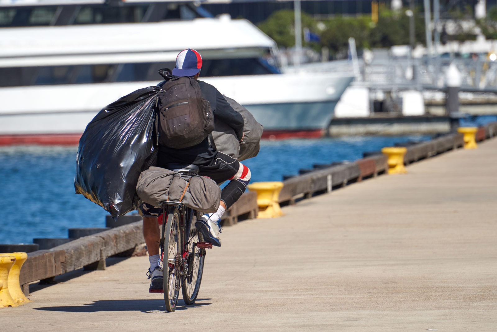 Homeless man riding his bicycle while carrying bags and backpacks