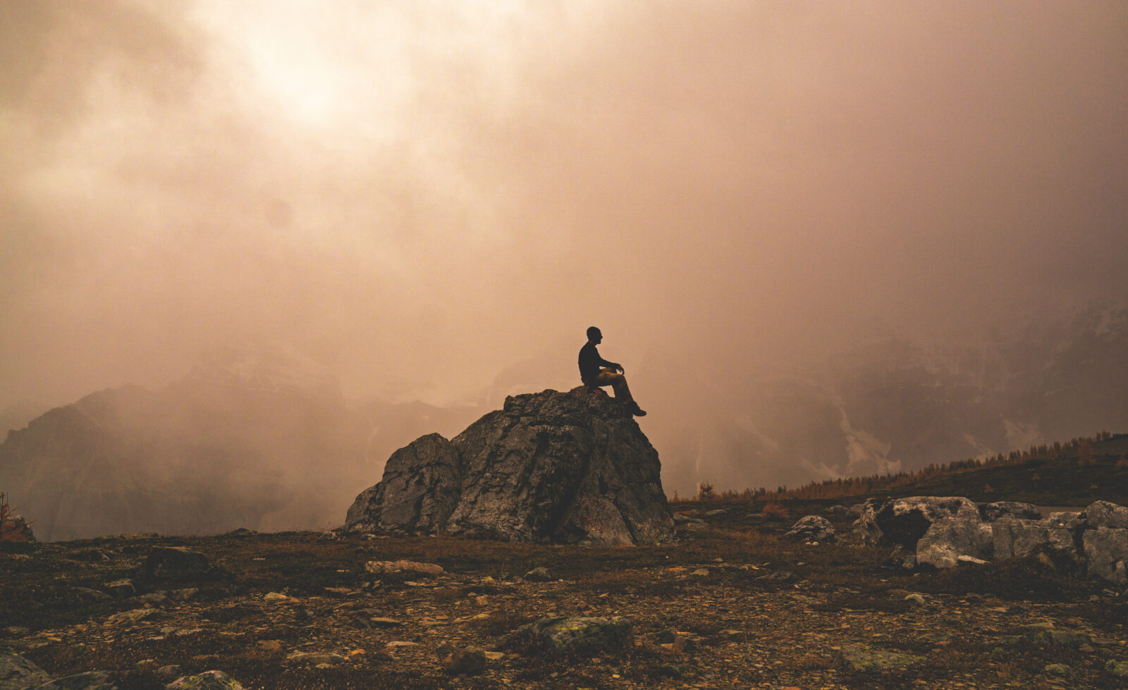 Contemplative Silhouette Sitting On Rock In Nature