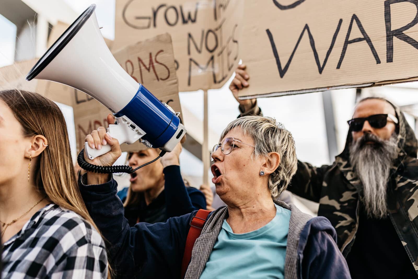 Diverse group of activists people holding posters and banners antiwar protesting against war and violence in the world.